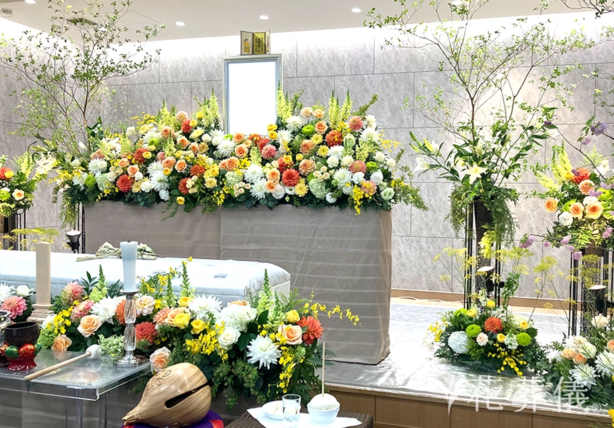 花祭壇のデザイン　白グリーンに、イエローオレンジのポイントで明るいお花でお飾りし、高低差や抜けるデザインがシンメトリーの美しい空間を演出